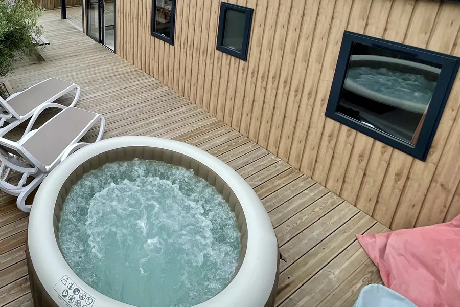Le spa du mobil-home Bora-Bora sur la terrasse en bois, deux transats et la façade en bois