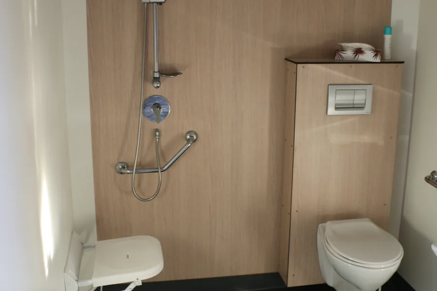 La salle d’eau du Glenans : douche avec siège rabattable et barres d’appui, WC suspendu